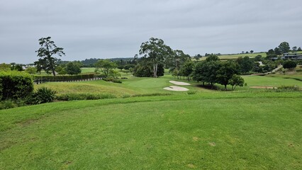 Lush green golf course landscape with sand traps and trees in the distance