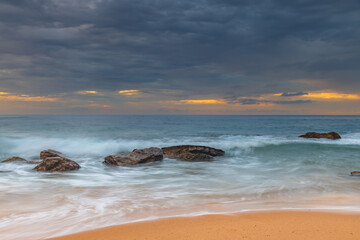 Sunrise at the seaside with rocks and beautiful diffused light by the rain clouds