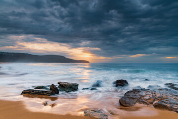 Sunrise at the seaside with rocks and beautiful diffused light by the rain clouds