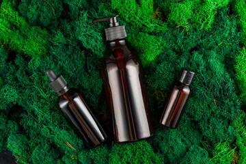 Brown glass dropper bottles arranged on green moss in a natural setting
