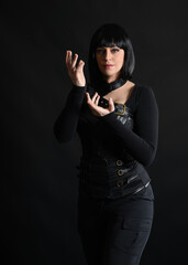 Close up portrait of beautiful black female model with short black hair wearing sci fi futuristic dystopian leather bodysuit costume.  isolated dark studio background moody silhouette.