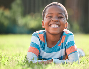 Boy, portrait and big smile in park on grass for summer, development and weekend break in field. Black child, happy and excited in nature for school vacation, relax and fun childhood with sunshine