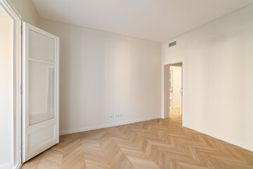 This is a spacious minimalist room featuring elegant herringbone flooring that impresses
