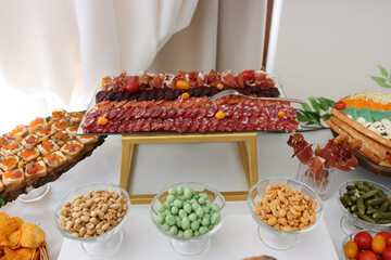 Buffet with smoked meats, salami, chips, nuts and tomatoes.