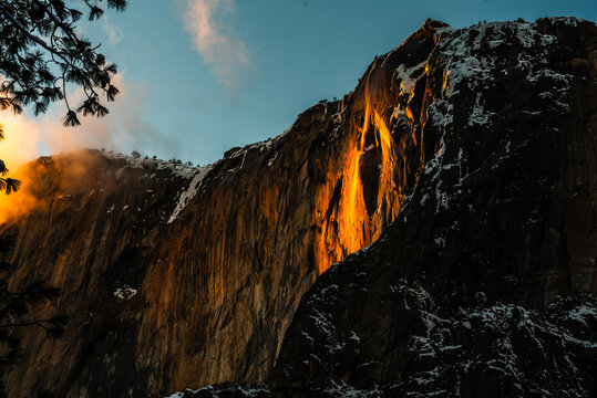 Yosemite's Firefall glowing orange on cliff during sunset in winter.