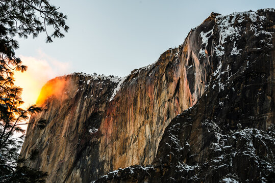 Yosemite's Firefall glowing at sunset over snow-covered cliffs