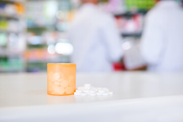 Container, tablets and medication on counter of pharmacy, prescription and pills at apothecary. Bottle, store and pharmaceutical service for medical treatment, antibiotics and jar for aspirin closeup