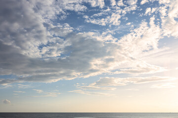 Obraz premium Darker dramatic clouds and sunlight beams at blue sky, capture from seaside