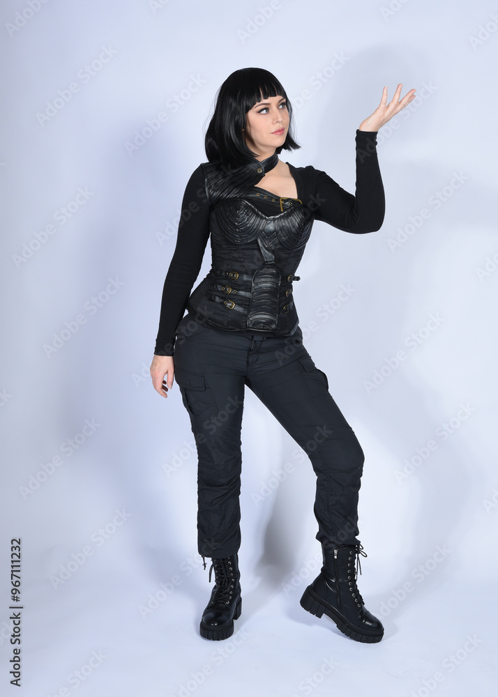 Canvas Prints Full length portrait of beautiful black female model with short black hair wearing sci fi futuristic dystopian leather bodysuit costume. Standing walking  pose, isolated white studio background.