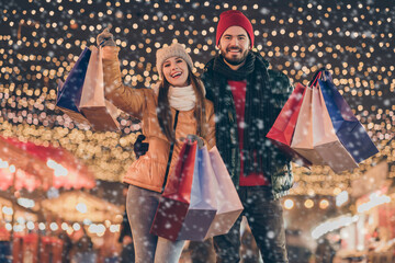 Black friday. Photo of two people friends raise buy shopping bags under x-mas christmas outdoors evening lights wear winter outerwear