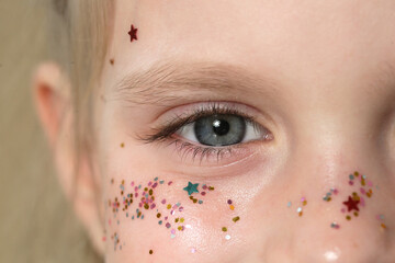 Close up of blue girl's eye with glitters around	