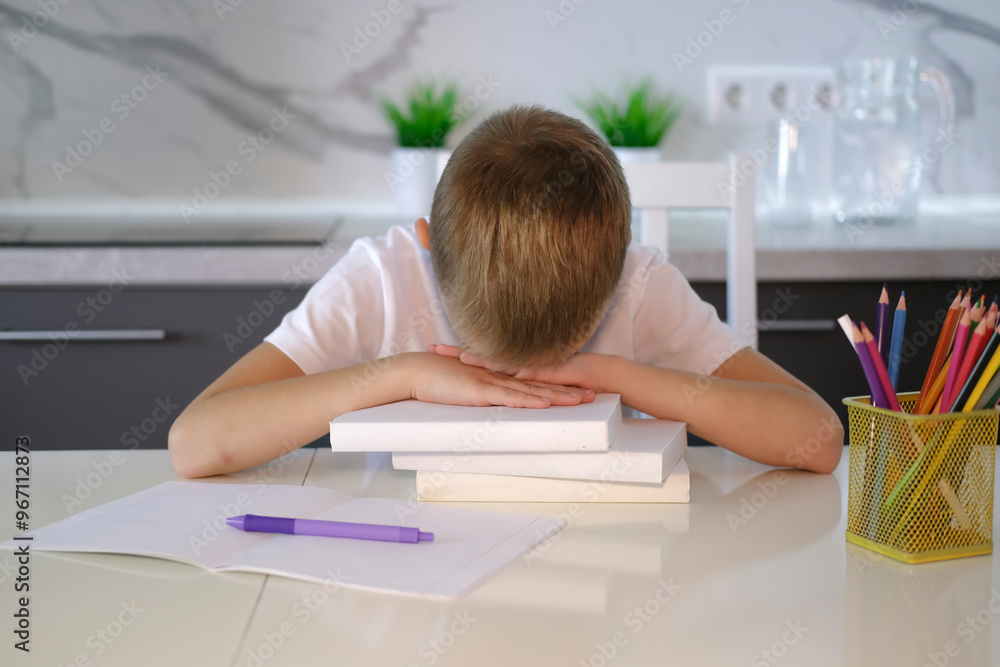 Wall mural portrait of tired, sad boy falling asleep at table while doing homework. child concentrates and focu