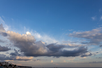 Darker dramatic clouds and sunlight beams at blue sky, capture from seaside