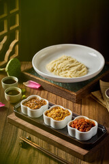 Dry mixed noodles with various seasonings on a wooden table indoors, close-up