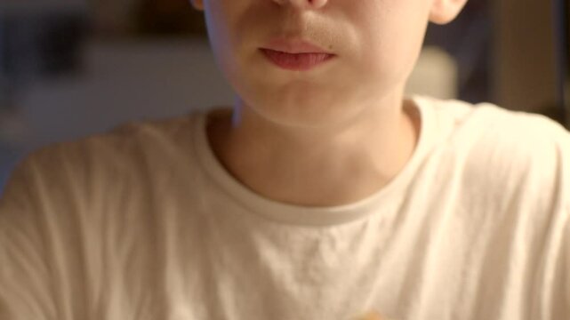 he eats french fries with his hands in the evening young boy pauses thoughtfully for a moment while enjoying a delicious meal in a softly dimly lit environment