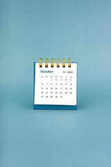 October 2024 white desk calendar on blue background.