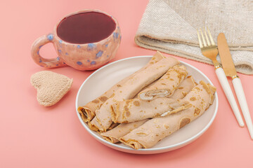 A cup of fragrant hibiscus tea and thin pancakes with cream. Good mood concept, cozy home comfort