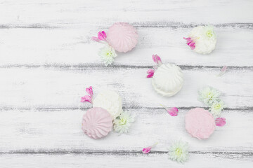 Fruit marshmallow with fresh flower petals on white wooden background. Lactose free vegan dessert