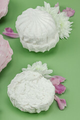 Obraz premium Fruit marshmallow with fresh flower petals on pastel green background. Lactose free vegan dessert