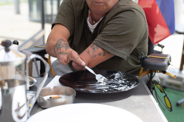 A focused individual is skillfully plating food outdoors, showcasing creativity and passion for culinary arts