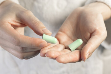 Woman is holding green earplug in hands