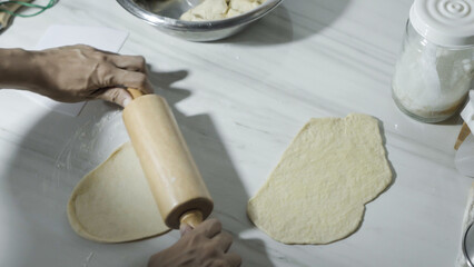 Steps Rolling the dough into a thin sheet and cutting it into long triangles on the dough of homemade croissant dough on the marble kitchen at home. Preparation food.