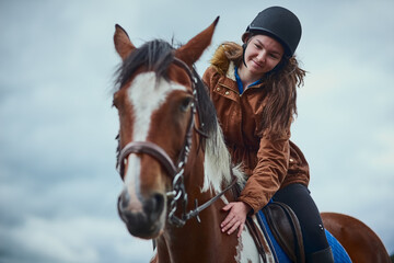 Horse, smile and child riding on farm for sport, countryside training and equestrian development. Below, girl and stallion balance for exercise practise, wellness hobby or ranch cloudy sky of support