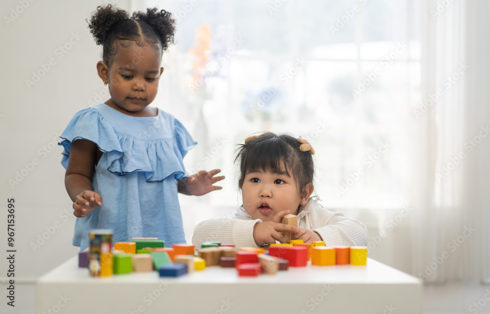 Wall mural two diverse children playing with colorful wooden blocks early childhood education, learning and dev