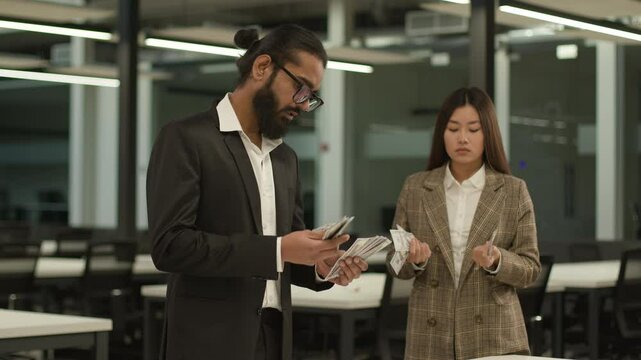 Inequality equal pay racial gender discrimination patriarchal world Indian business man Asian woman in office counting money finance salary cash payment two diverse colleagues financial gap injustice
