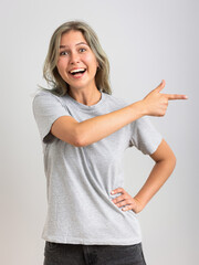 Amazed girl wearing gran tee-shirt pointing finger at blank copy space.