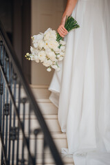 A delicate white bouquet in the hands of the bride. An addition to the wedding look. Floral compositions for the holiday.