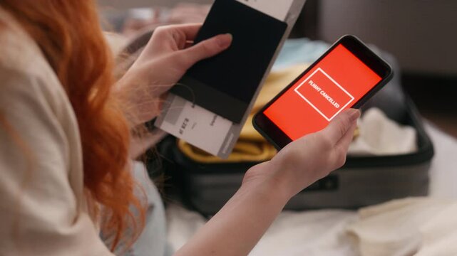 Unrecognizable traveler woman at bedroom holding mobile phone red screen sms message notification airline cancelled flight cancel problem female girl preparing trip travel trouble tickets passport