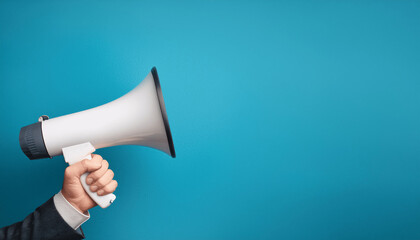 Hand holding a white megaphone on a blue background- announcement, communication, marketing