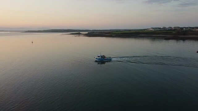 Small fishing boat leaving wake ripples in early morning glowing sunlit sunrise ocean seascape