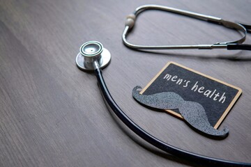 A stethoscope next to a chalkboard with the words “men’s health” and a mustache cutout....