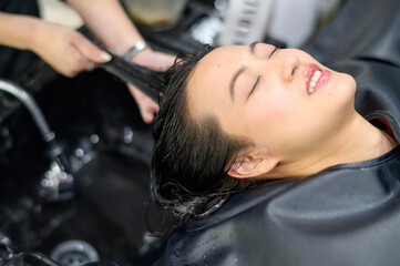 Fototapeta premium A woman enjoying hair wash at salon, expressing relaxation and contentment.