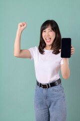 Woman in a white t-shirt smiling and holding a smartphone with a happy expression on a green background, showing satisfaction.