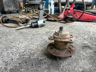 A close-up view of a mechanical part on a workshop floor, showcasing its worn texture and details, evoking a sense of industrial work and repair.