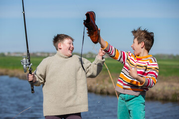 Funny fishing. Two of the boy's friends hooked an old shoe with a fishing rod and are laughing.