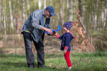 Grandfather and grandson launch an airplane during a walk in the forest. Family having fun in nature. Playing with grandson.