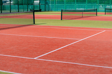 The tennis court is empty with a net and a green fence.