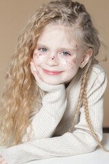 Portrait of cute little blonde girl with blue eyes and glitters on her face.	