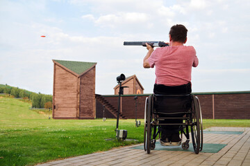 A middle-aged man of European appearance shoots at a clay pigeon flying from right to left