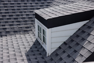 A roof with a garret window and roof shingle.