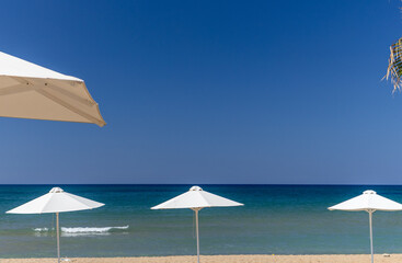 sandy beach with white sun umbrellas and turquoise sea, seaside vacation concept