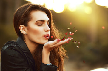 Fototapeta premium Nature, freedom and woman blowing confetti on field with hope, wish or optimism in countryside. Face, beauty and female person in park with flower petals, peace and superstition in outdoor travel