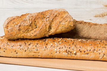 Freshly baked bread on cutting board against white wooden background. perspective view bread with copy space