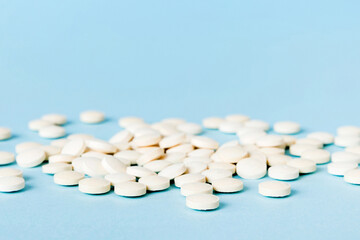 Heap of white pills on colored background. Tablets scattered on a table. Pile of red soft gelatin capsule. Vitamins and dietary supplements concept
