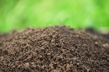 fertile pile of soil with green grass blurred background