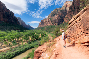 Rear view of woman standing at the cliff edge enjoying view from Zion National Park Canyon...